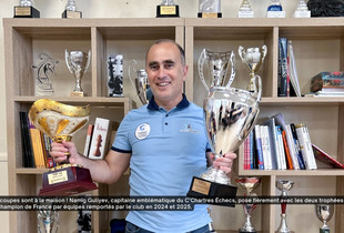 Le capitaine de l'équipe de C'Chartres échecs pose avec les deux trophées de champion de France par équipes.