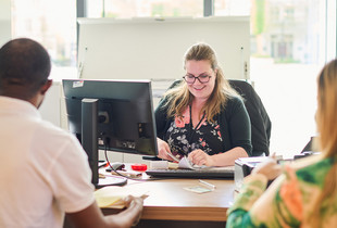 Une employée municipale recevant des personnes pour effectuer des démarches administratives.