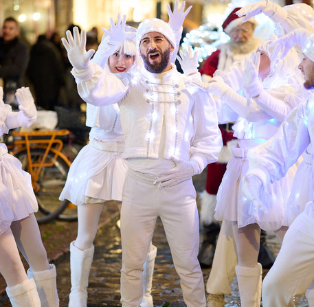 Portrait d'un animateur de No&euml;l entour&eacute; d'autres danseurs dans une rue de Chartres.