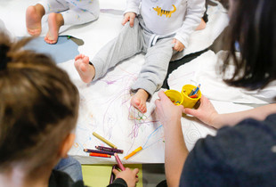 Jeunes enfants coloriant sous le regard d'une éducatrice
