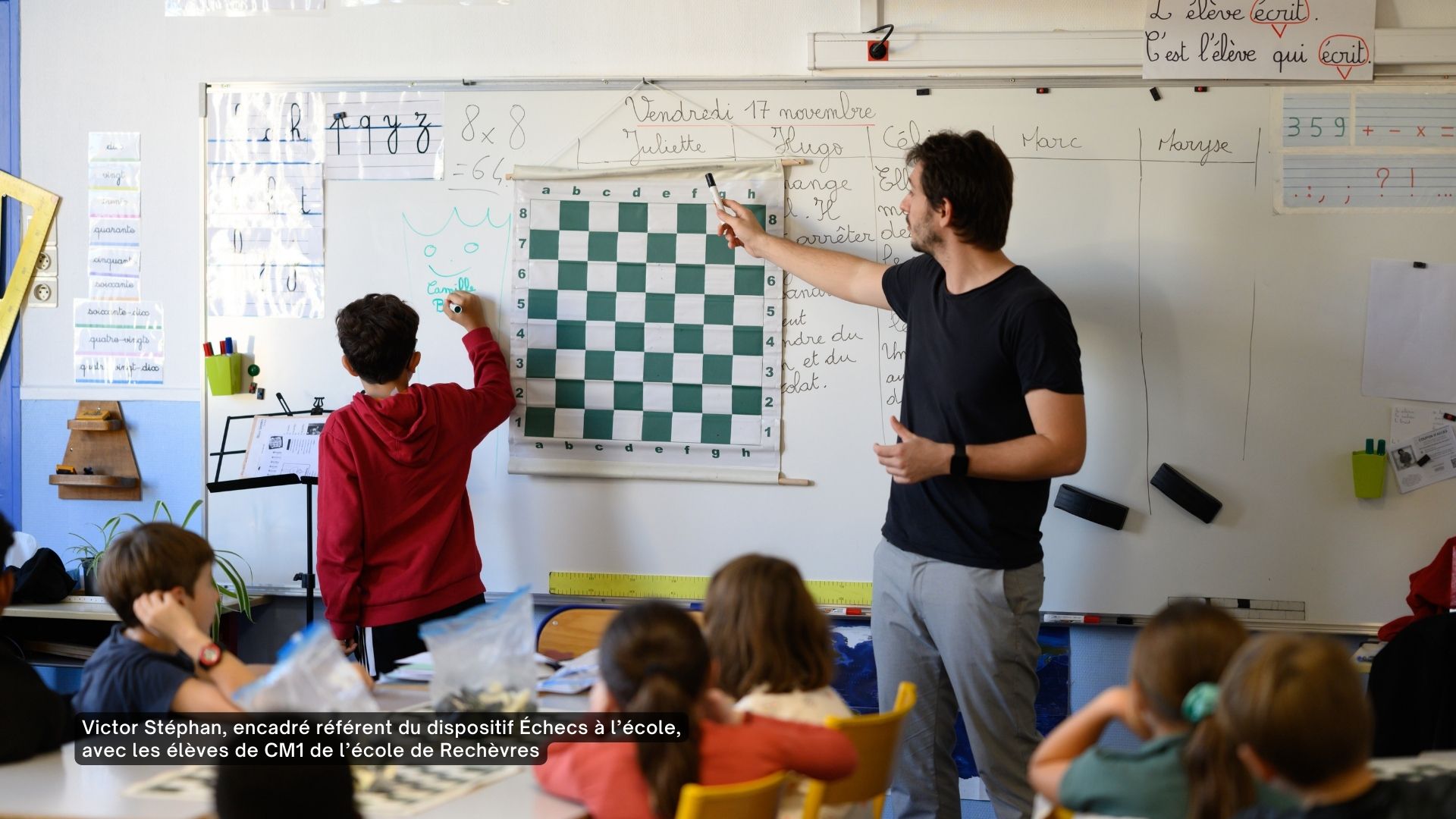 Un professeur devant un tableau enseignant les Échecs à une classe de CM1