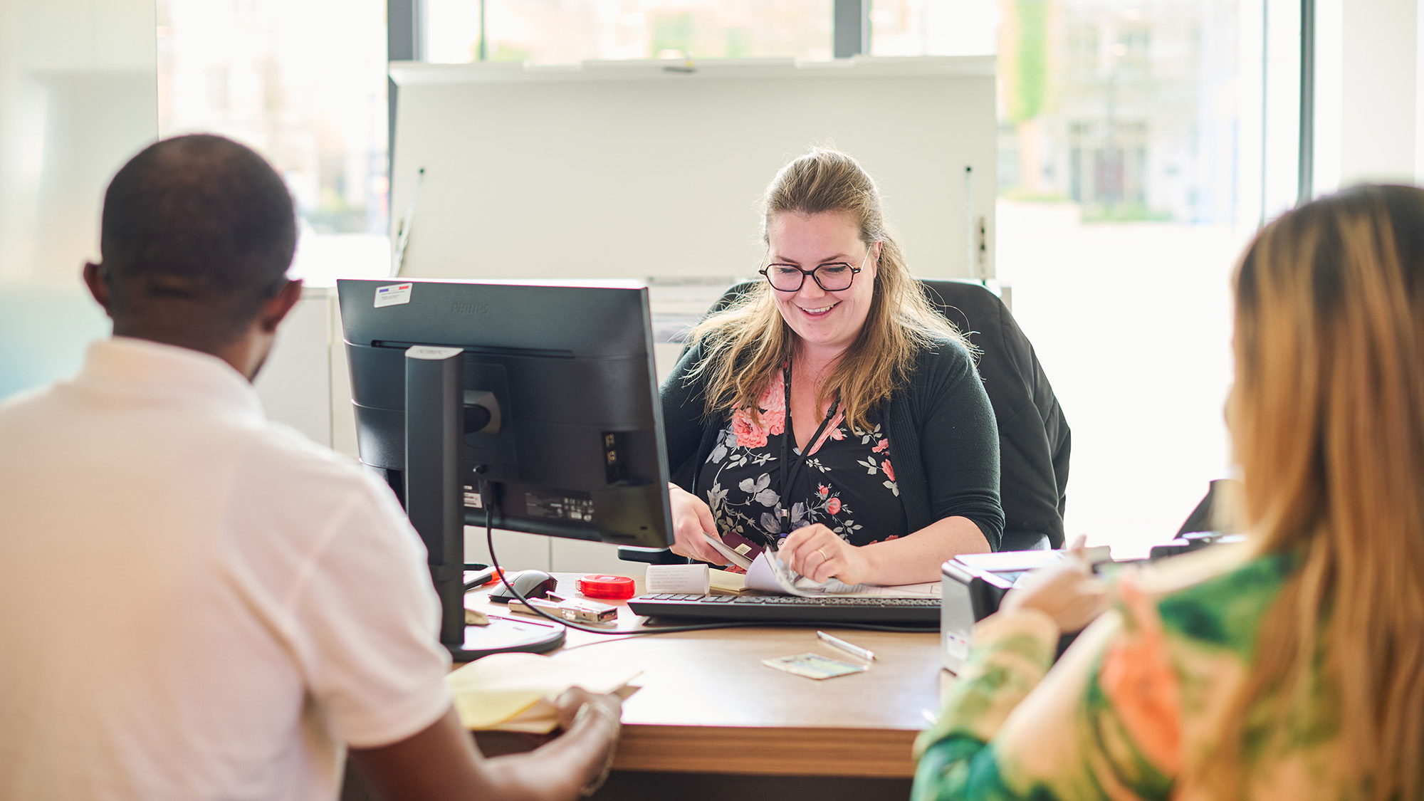 Une employée municipale recevant des personnes pour effectuer des démarches administratives.