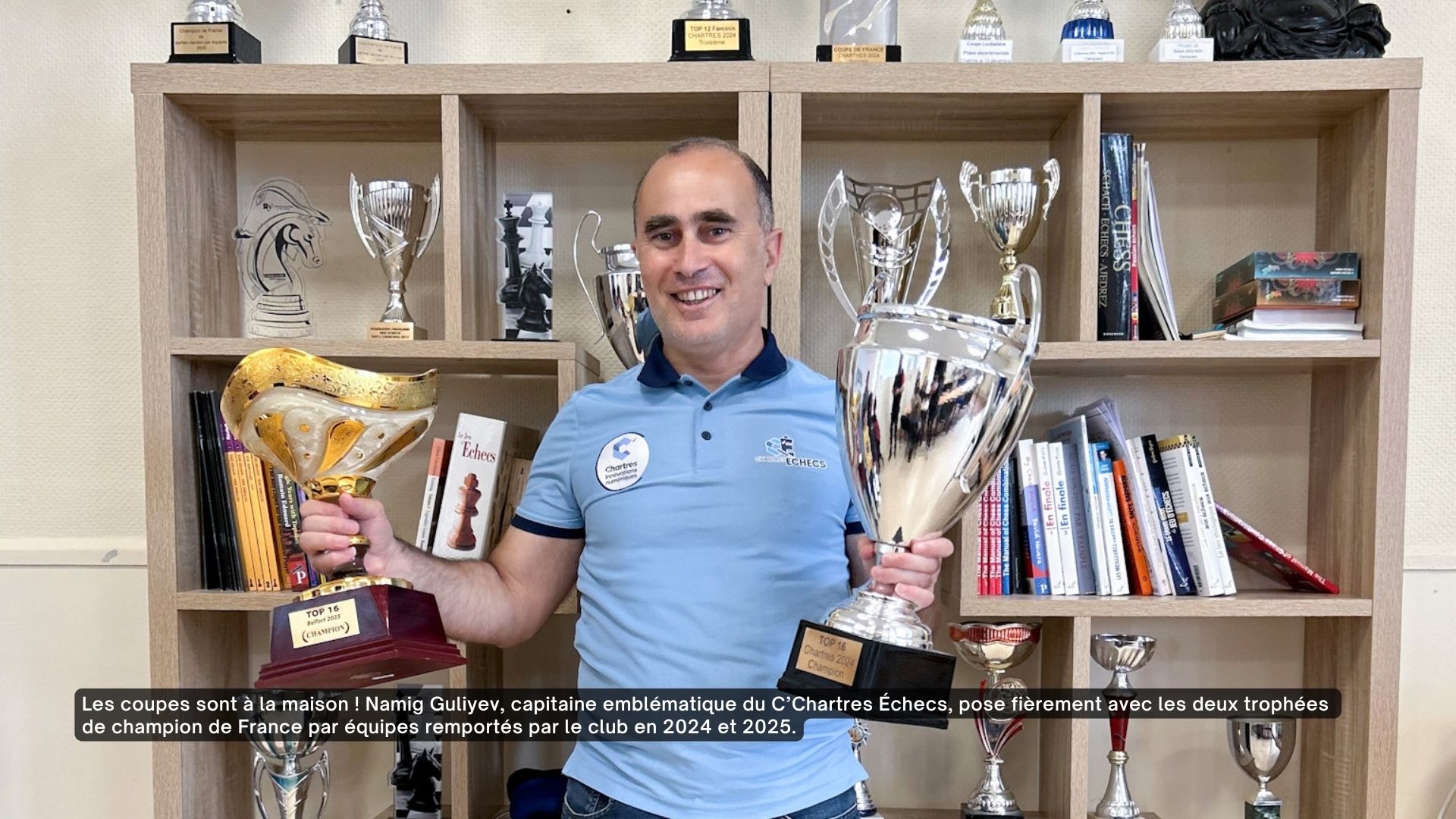 Le capitaine de l'équipe de C'Chartres échecs pose avec les deux trophées de champion de France par équipes.